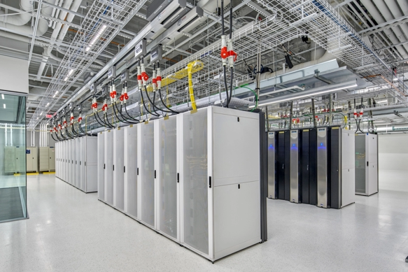 A man standing in front of a server rack, managing and monitoring the network infrastructure.